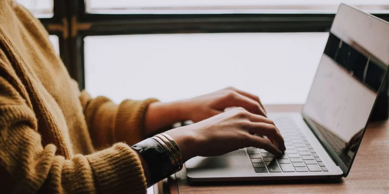 Person Typing on Computer At Desk Inside